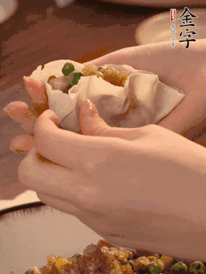 取一大勺餡料放進(jìn)餃子皮里，用大拇指按住頂部餡料，再用虎口掐出形狀。